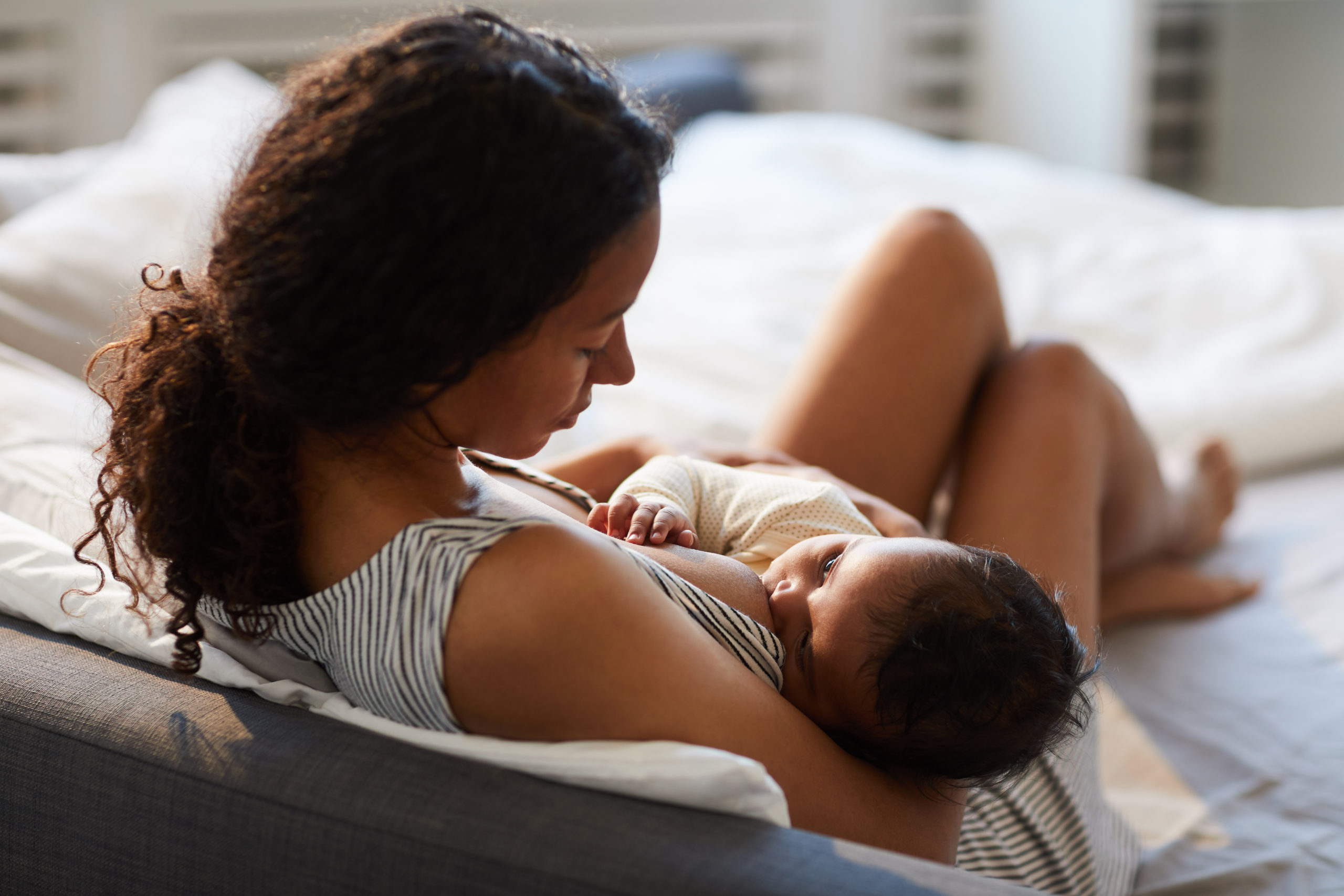 Peaceful,Loving,Young,African,Mother,Sitting,On,Bed,And,Leaning